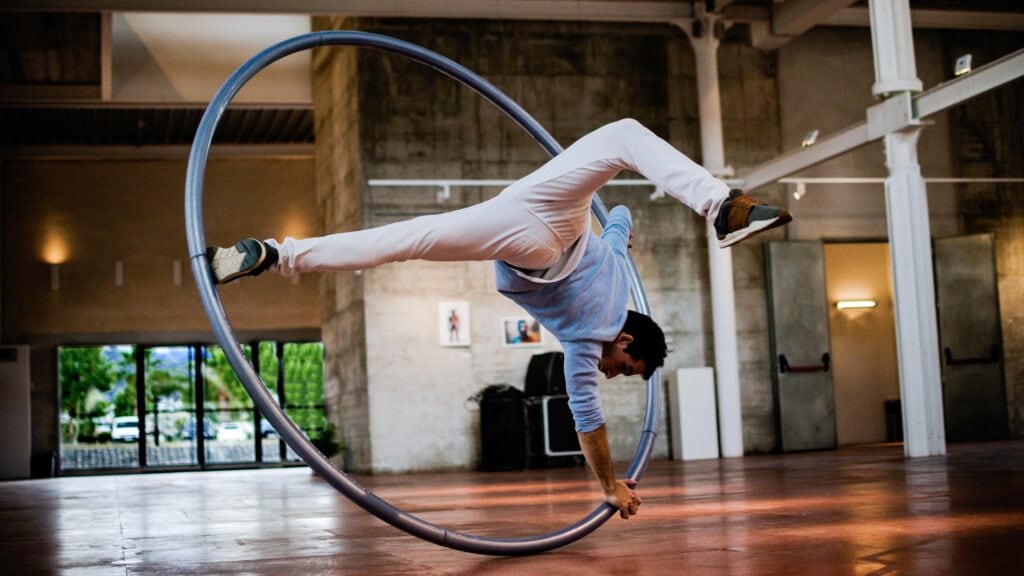 A man doing a wheel balancing on a hula-hoop.