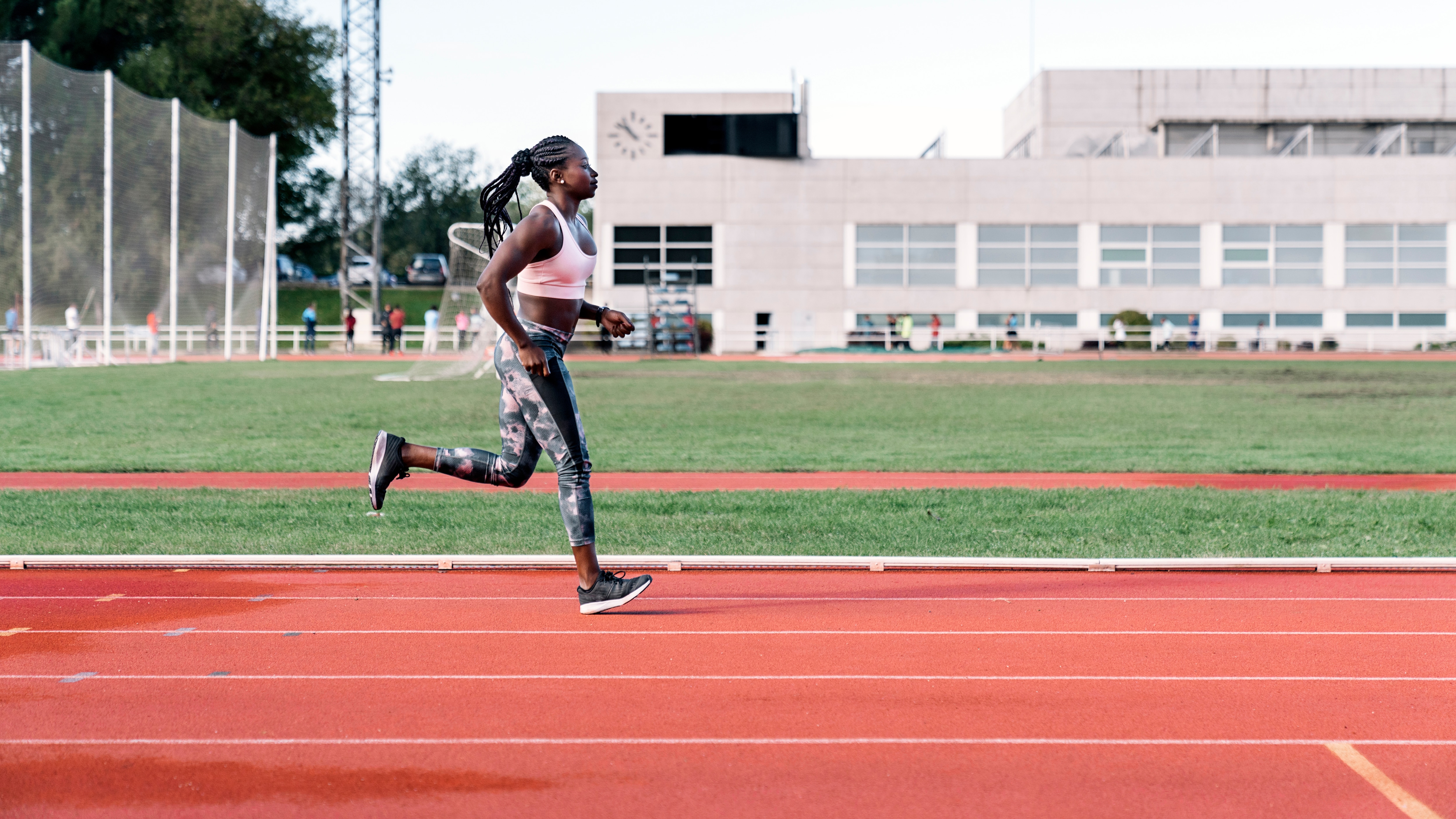A Black woman running on a professional running track.