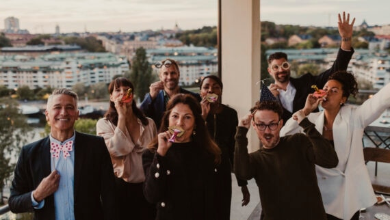 A group of diverse people celebrating on a balcony.