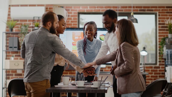 A group of people standing around a table shaking hands.