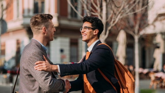 Two  young businessmen greeting each other in the city centre