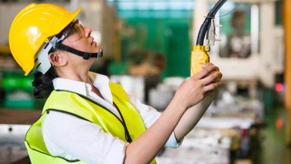 A woman in a yellow hard hat in an industrial setting