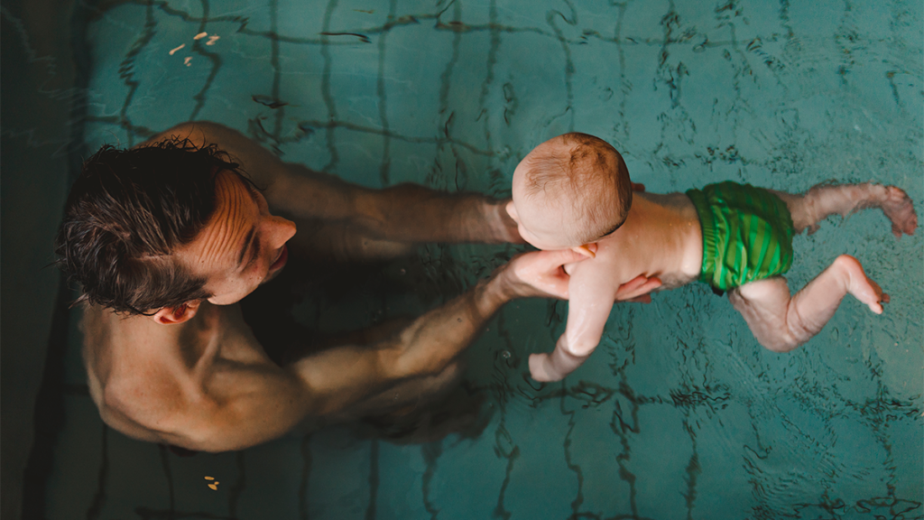 A father enjoying time off from work swimming with his young child