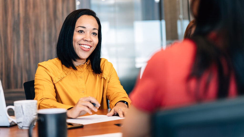 Two women engaged in a job interview, sitting across from each other at a table