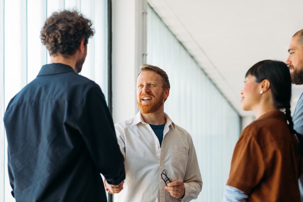 A small group of colleagues greeting a new member of staff on their first day of work in a modern office environment