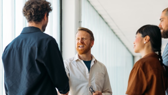 A small group of colleagues greeting a new member of staff on their first day of work in a modern office environment
