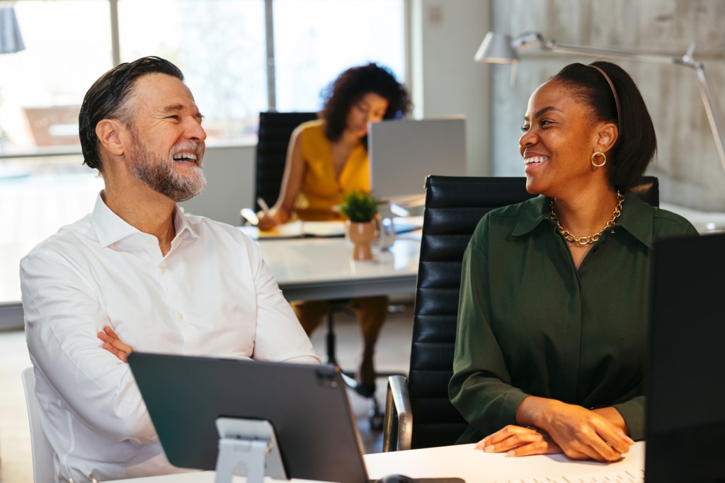 Two colleagues sharing a joke in the office, suggesting a relaxed, productive, and engaging workplace environment