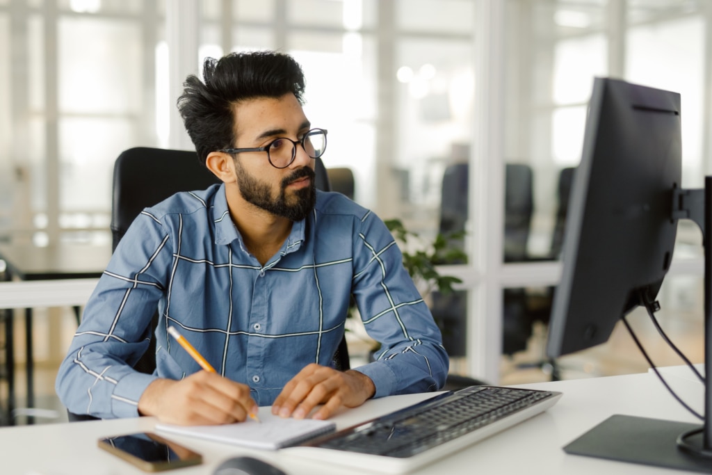 A busy male employee making notes on candidates during the screening process