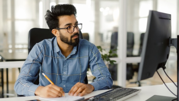 A busy male employee making notes on candidates during the screening process