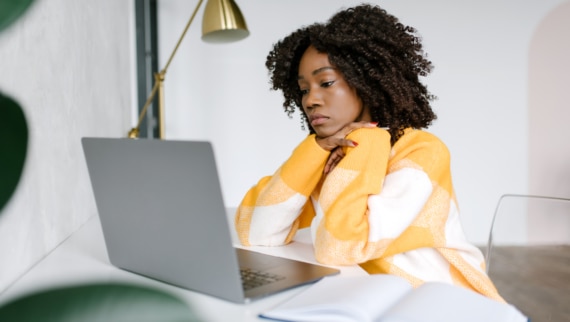 Young professional woman showing signs of fatigue while working on a laptop, illustrating the importance of employee burnout prevention and mental health awareness in the workplace.