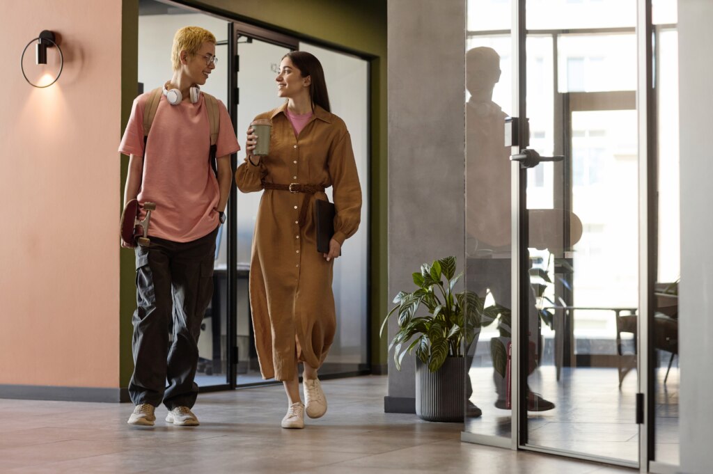 Gen Z colleaguues having small talk while walking along corridor to their office