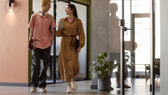 Gen Z colleaguues having small talk while walking along corridor to their office
