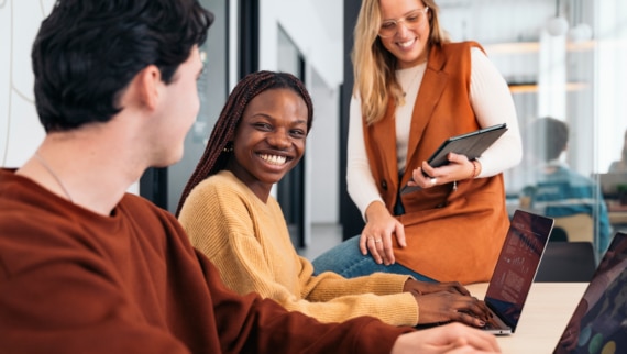 Smiling diverse professionals collaborating in a modern office setting, representing a successful hiring process and strong team fit — illustrating strategies to improve quality of hire
