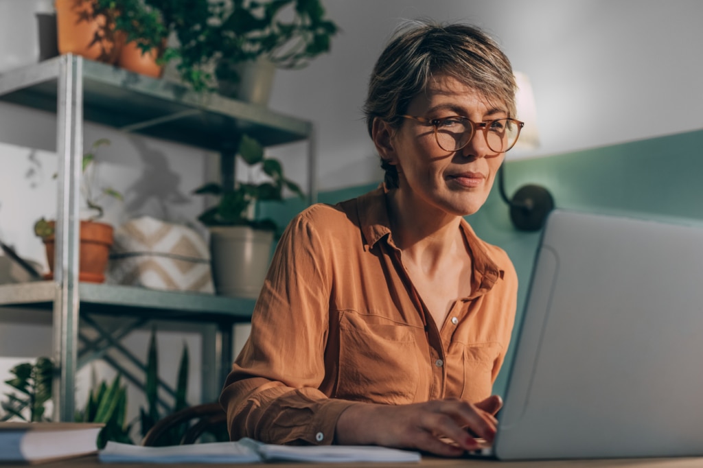 A woman in her 50s working on a laptop from home posting a job advert online