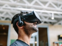 Man wearing a virtual reality headset and headphones indoors, looking upwards as he experiences immersive technology.