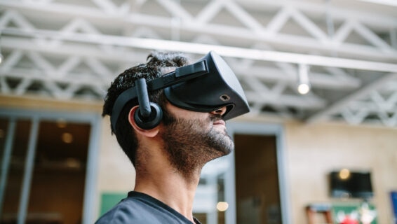 Man wearing a virtual reality headset and headphones indoors, looking upwards as he experiences immersive technology.