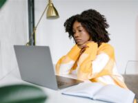 Employee looking uncertain while working on a laptop at home