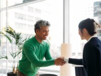 Woman and man smiling and shaking hands after successful job interview