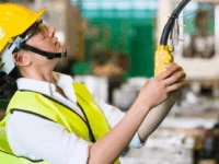 A woman in a yellow hard hat in an industrial setting