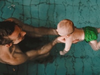 A father enjoying time off from work swimming with his young child