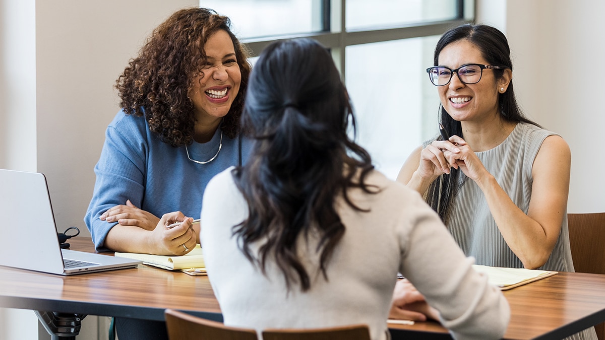 Group of women discussing a topic with joy in a professional setting