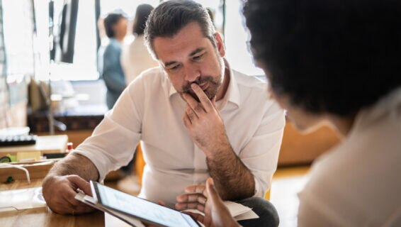 Mature man looking at a digital tablet that a colleague is showing at work