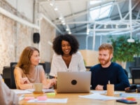 Hiring Trends Update Three colleagues working on a laptop in a modern office environment