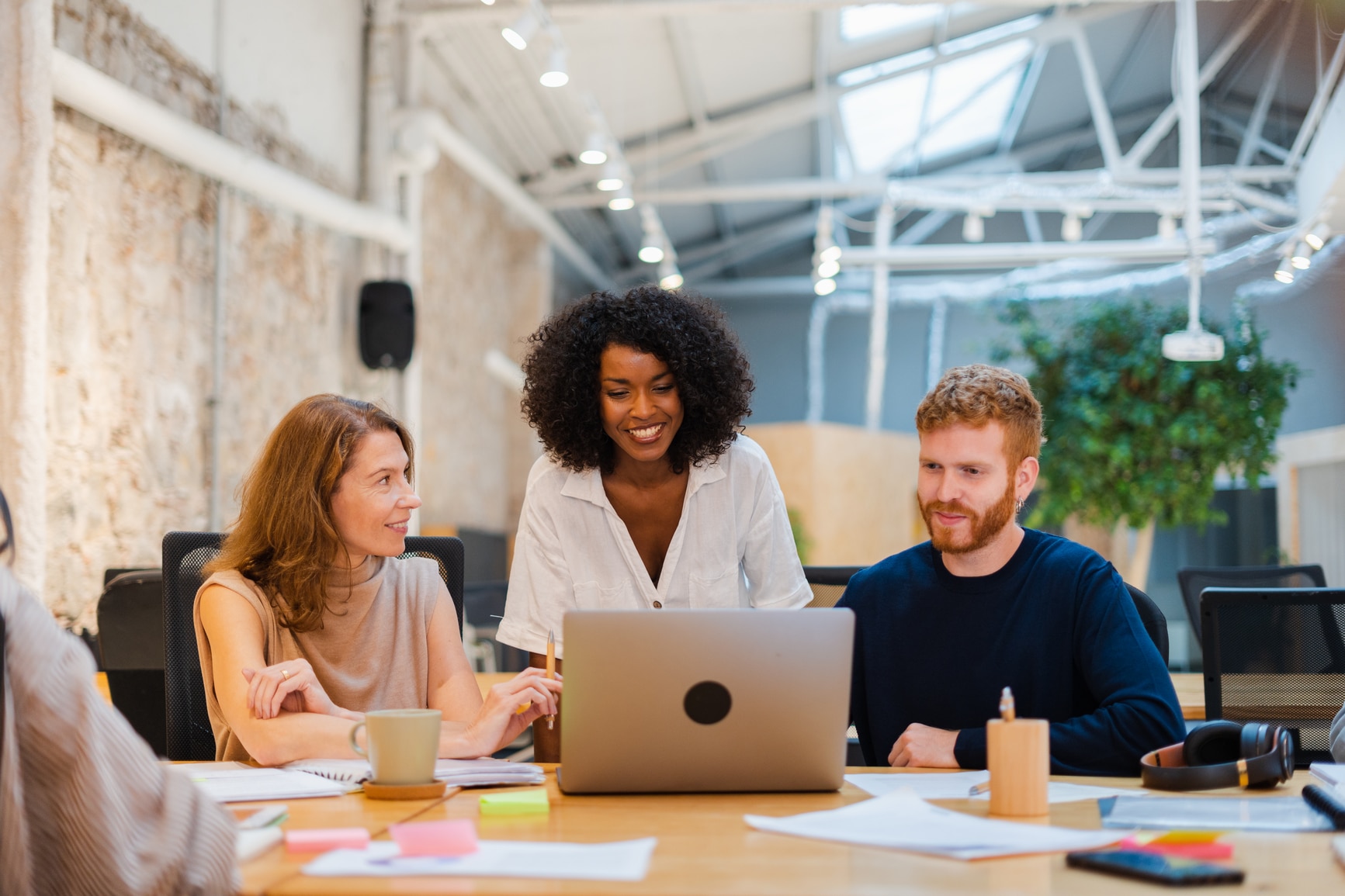 Three colleagues working on a laptop in a modern office environment