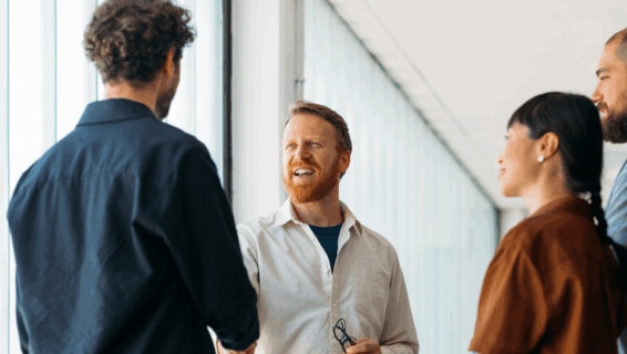 A small group of colleagues greeting a new member of staff on their first day of work in a modern office environment