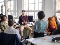 A group of workers applauding one of their colleagues in an office environment