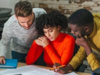 Group of young multiethnic men and woman coworking on new plant draft sitting at desk