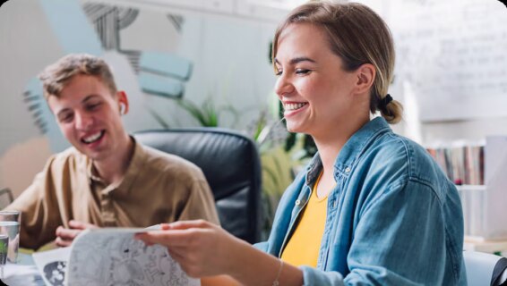 A young woman and a young man looking at a notebook and smiling