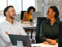 Two colleagues sharing a joke in the office, suggesting a relaxed, productive, and engaging workplace environment