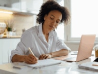 Focused woman making notes from her laptop, demonstrating the work that goes into implementing skills-based hiring