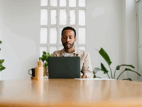 A manager in casual outfit typing on laptop keyboard while sitting at desk and working on business project in stylish office.