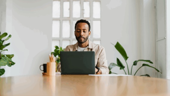 A manager in casual outfit typing on laptop keyboard while sitting at desk and working on business project in stylish office.