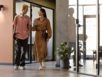 Gen Z colleaguues having small talk while walking along corridor to their office