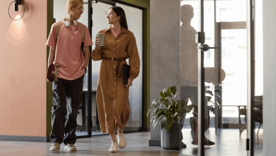 Gen Z colleaguues having small talk while walking along corridor to their office