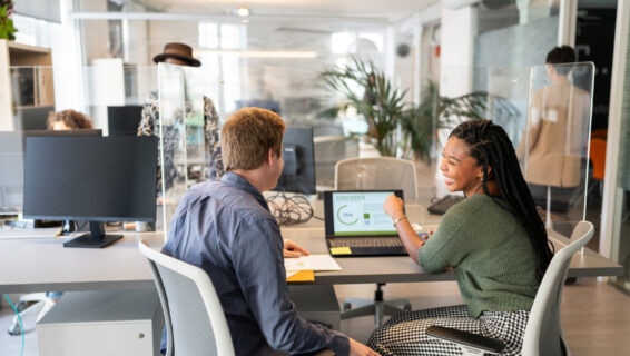 Two colleagues in a modern office discussing recruitment statistics on a laptop, illustrating hiring trends 2026 and skills-focused workforce planning.