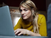 An image of a woman looking at her laptop screen.