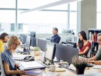 An image showing a group of people working at their desks in an office.