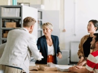 Workers greeting a new colleague, suggesting the importance of a quick time to hire to get new employees onboard quickly