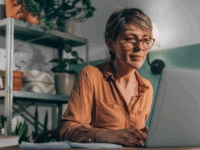 A woman in her 50s working on a laptop from home posting a job advert online