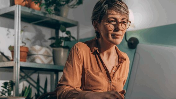 A woman in her 50s working on a laptop from home posting a job advert online