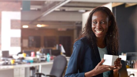 Black woman smiling in the office holding a small box