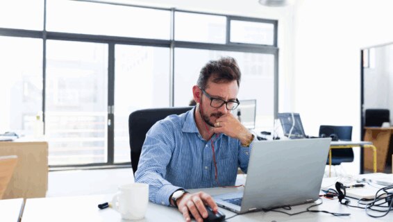 A recruiter working behind a desk in an office environment. His concerned expression suggests he is facing a number of potential recruitment challenges