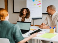 Three colleagues sitting across from each other in an office setting