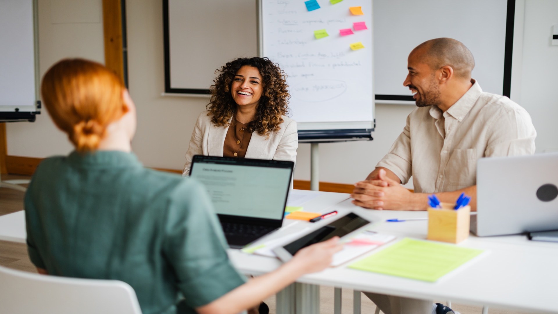 Three colleagues sitting across from each other in an office setting