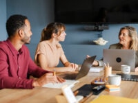 A group of diverse colleagues discussing a business plan in an office environment, highlighting how skills based hiring can bring together diverse teams of talent individuals to drive organisational success