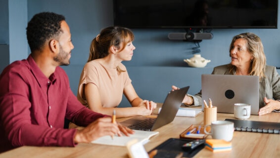 A group of diverse colleagues discussing a business plan in an office environment, highlighting how skills based hiring can bring together diverse teams of talent individuals to drive organisational success